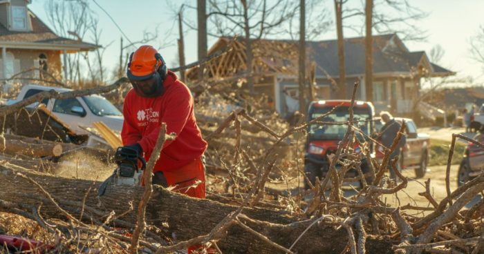 Team Rubicon volunteer chainsawing a fallen tree